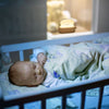 Veilleuse Grille Pain éclairant doucement un bébé endormi dans son berceau.