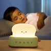 Veilleuse Grille Pain éclairant doucement un enfant endormi dans son lit.