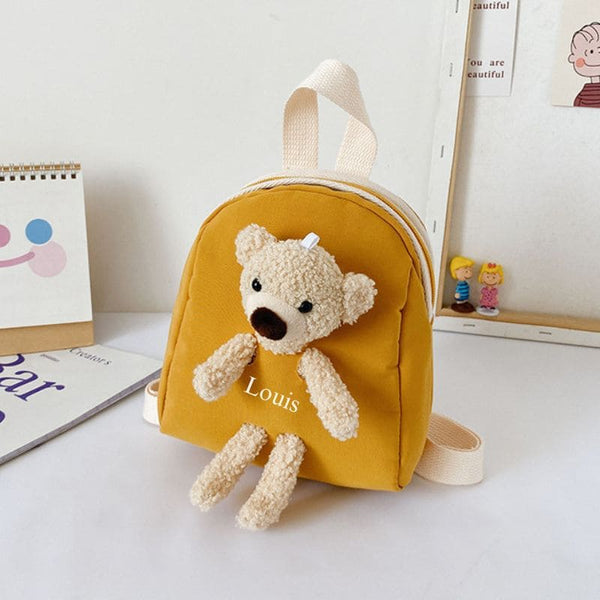 Sac à dos maternelle jaune avec prénom "Louis", peluche ourson adorable en façade.