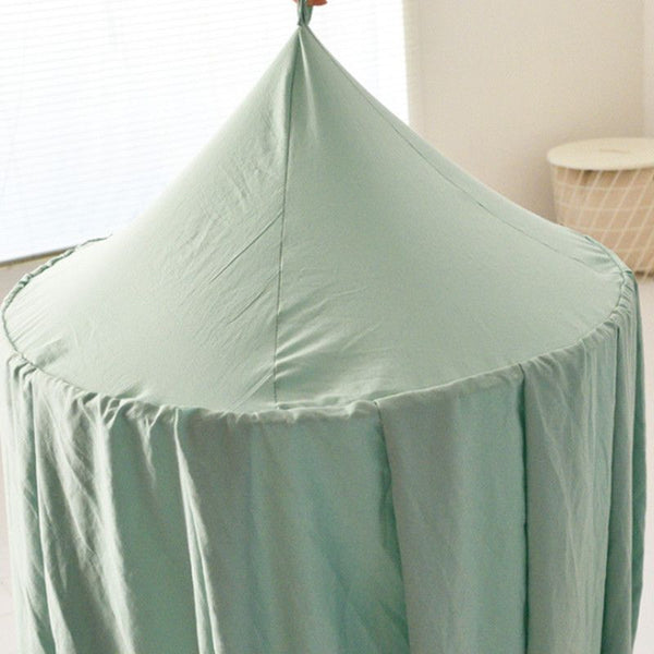 Ciel de lit bébé vue de dessus, montrant un dôme vert clair avec un tissu fluide.