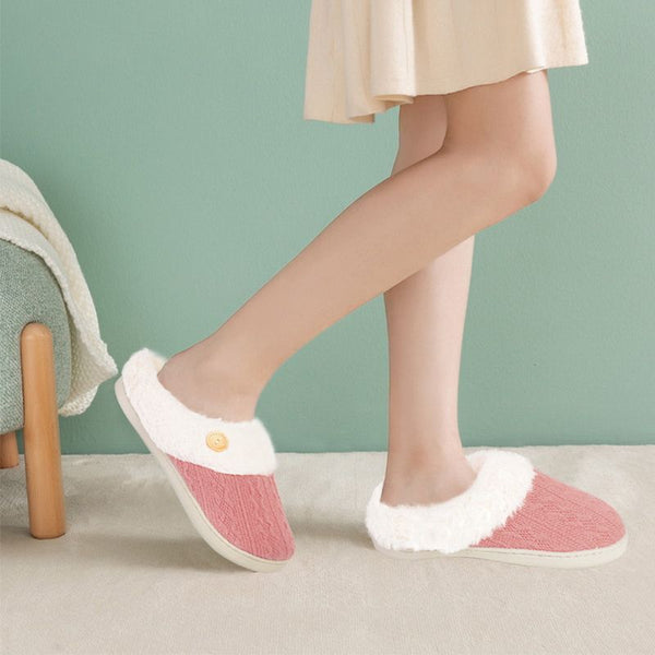 Femme portant des chaussons fourrés Femme rose dans une pièce au mur vert.