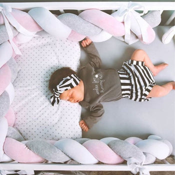 Bébé paisiblement endormi dans un lit avec une tresse de lit bébé Gris-Blanc-Rose.