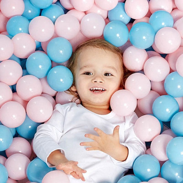 Enfant jouant dans une piscine remplie de balles pour piscine à balles roses et bleues.