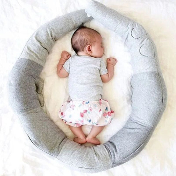 Tour de lit bébé crocodile gris formant un nid douillet autour d'un nourisson.