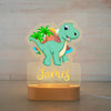 Veilleuse bébé personnalisée avec un dinosaure vert et un décor volcanique, prénom James en lumière douce.