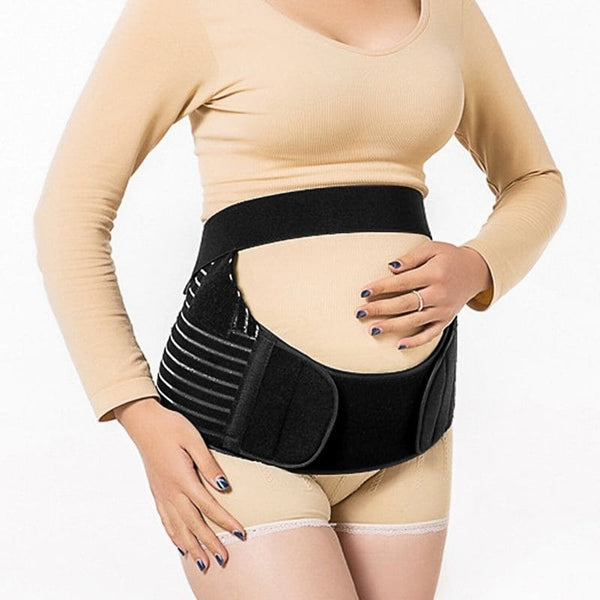 Femme enceinte en tenue beige portant une Ceinture de Soutien de Grossesse noire avec un design rayé.