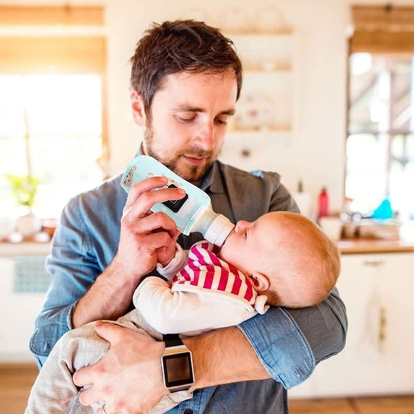 Papa nourrissant son bébé avec le chauffe biberon nomade.