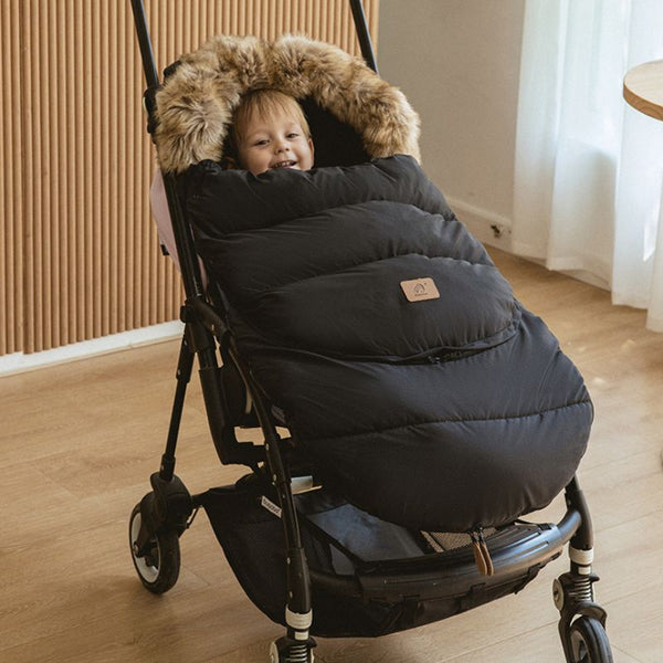 Chancelière universelle évolutive FlexiCocon noire installée sur une poussette, offrant une protection thermique optimale pour bébé.
