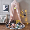 Ciel de lit bébé rose dans un espace de jeu avec des coussins et des décorations étoilées.