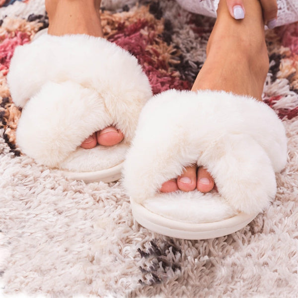 Chaussons Confortable Femme blancs portés sur un tapis chic blanc et rose.