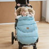 Petite fille dans une poussette équipée de la chancelière universelle évolutive FlexiCocon bleue, col en fourrure pour plus de chaleur.