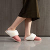 Femme debout portant des Chaussons Chauds Femme roses pour un look élégant.