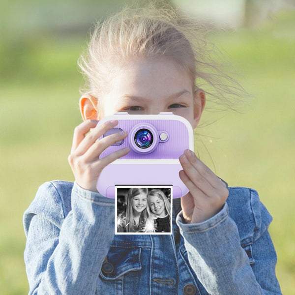 Enfant tenant un appareil photo jouet violet avec un arrière-plan flou - Appareil Photo Enfant Impression Instantanée Sans Encre