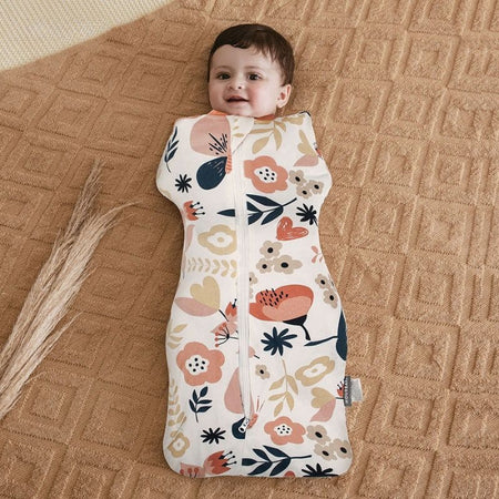 Bébé souriant emmailloté dans un Lange d’Emmaillotage fleuri coloré