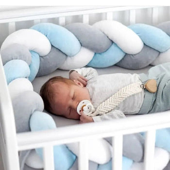 Bébé paisiblement endormi dans un lit avec une tresse de lit bébé Gris-Blanc-Bleu.