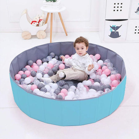 Enfant s'amusant dans une piscine à balles bébé avec des couleurs pastel.