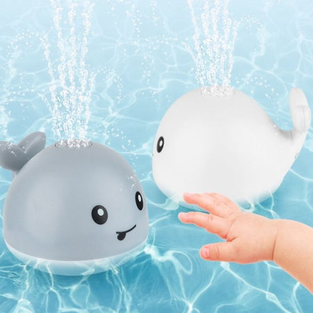 Jouet de bain bébé Luna la baleine flottant sur l'eau avec un bébé tendant la main.