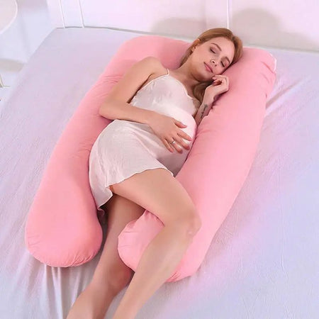 Femme enceinte allongée avec le Coussin de Grossesse U rose pour un soutien optimal.