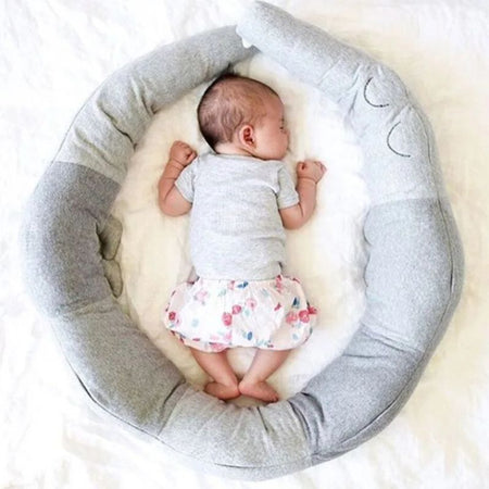 Tour de lit bébé crocodile gris formant un nid douillet autour d'un nourisson.