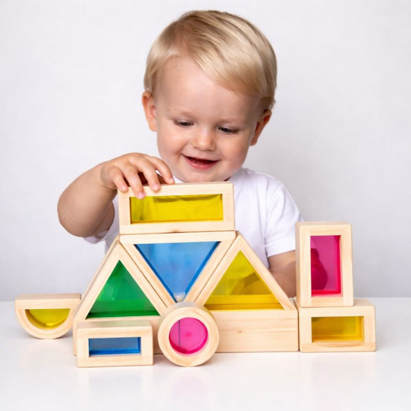 Jeune enfant empilant les blocs en bois LumiBlocks à panneaux translucides colorés sur une table - Cocon d'Ange