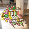 Blocs LumiBlocks alignés au soleil projetant des ombres colorées sur le parquet - Cocon d'Ange