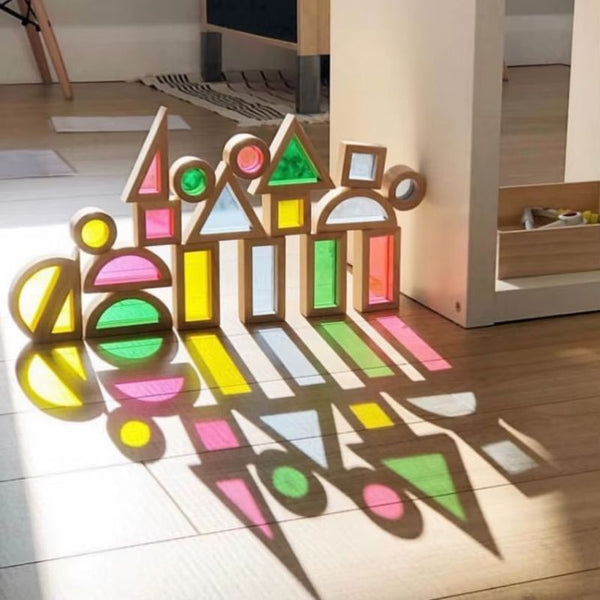 Blocs LumiBlocks alignés au soleil projetant des ombres colorées sur le parquet - Cocon d'Ange