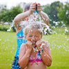 Enfant recevant l'eau d'une bombe SplashBall vidée au-dessus de sa tête dans le jardin - Cocon d'Ange
